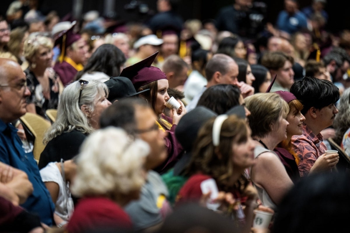 Woman drinking out of small Starbucks cup in crowd