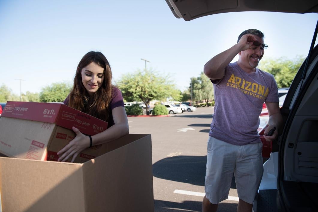 A student unloads her belongings from her family's car at the West campus.