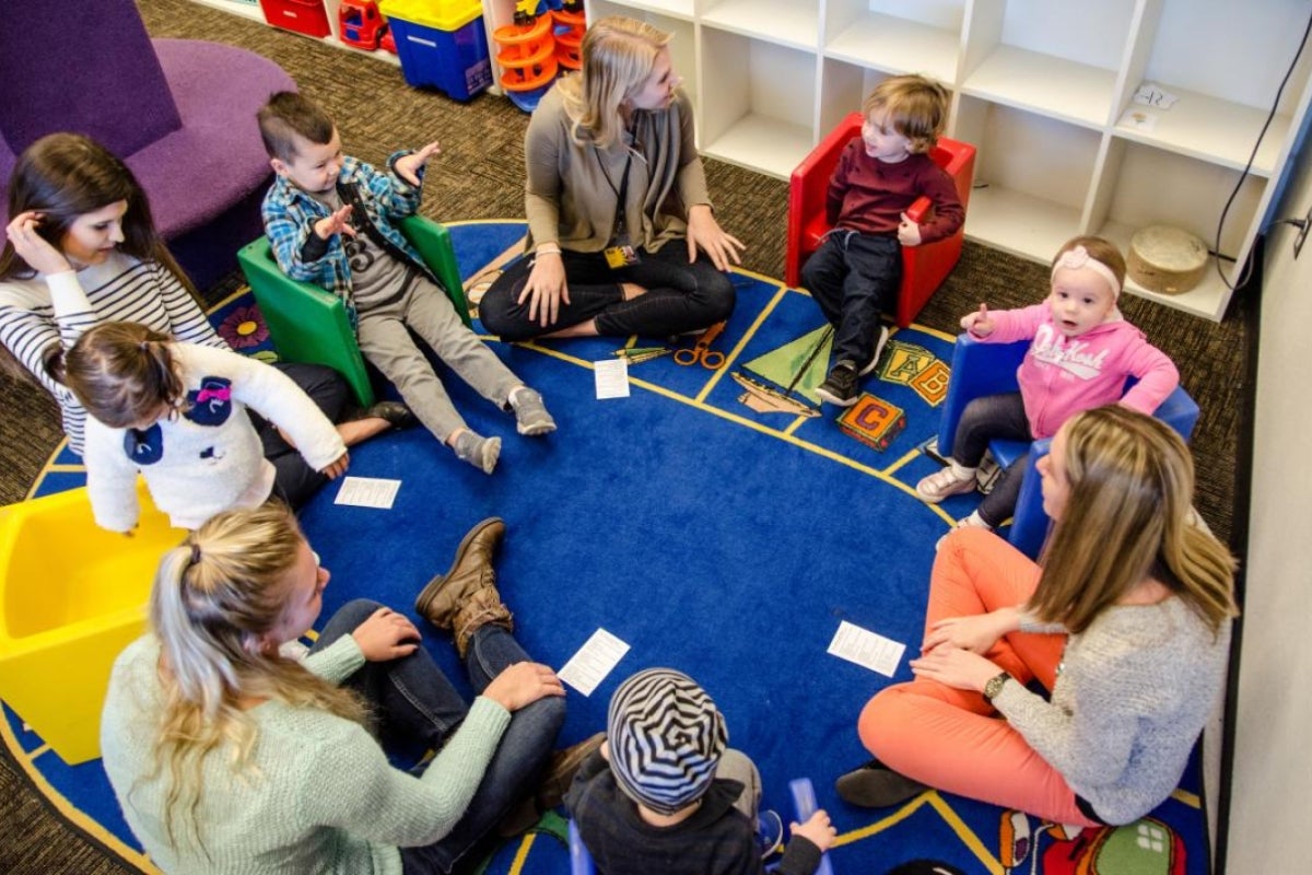 ASU speech and hearing science students and toddlers singing in a circle in a classroom