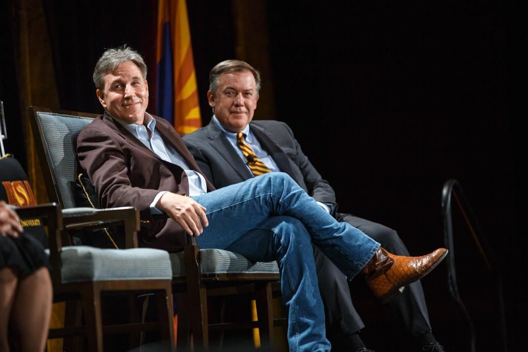 two men sitting in chairs on stage