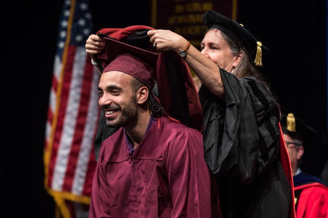 professor placing hood on graduate