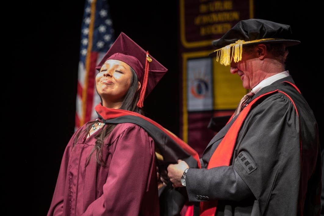 professor adjusting hood on graduate