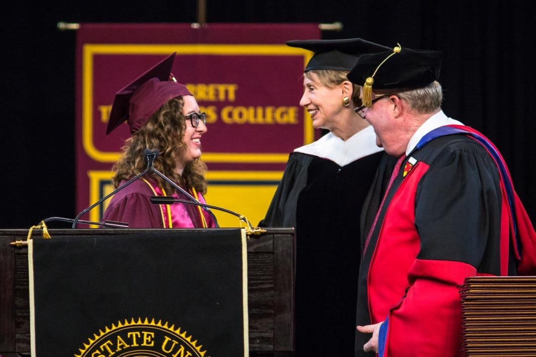 three people on stage at graduation