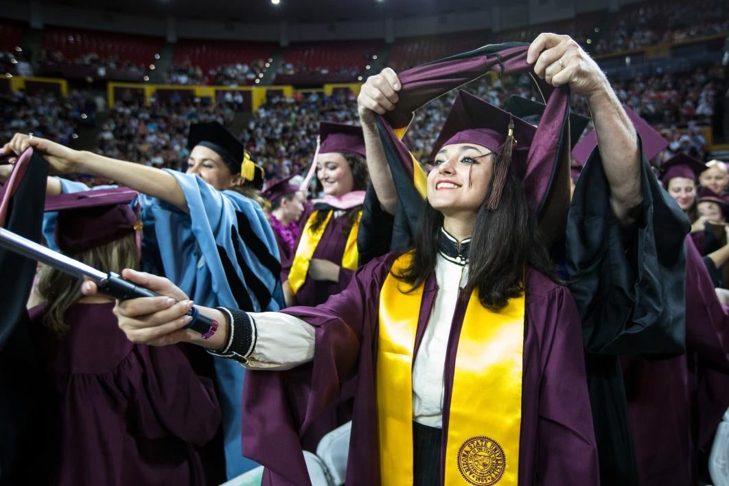 professor placing hood on graduate