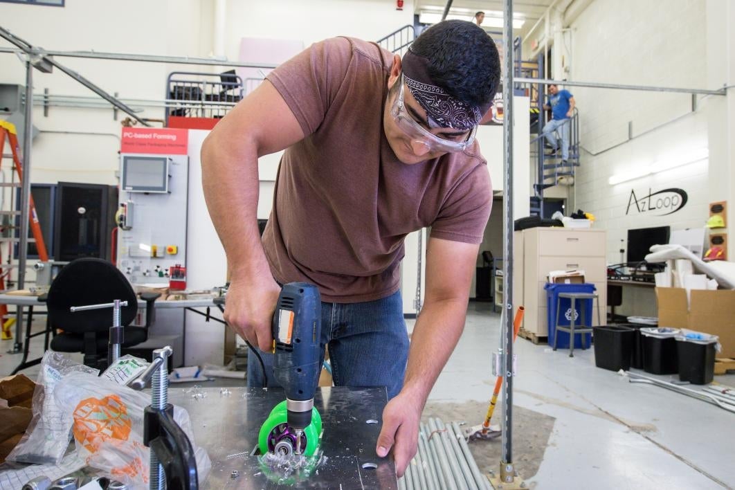 A man attaches polymer wheels to a metal plate