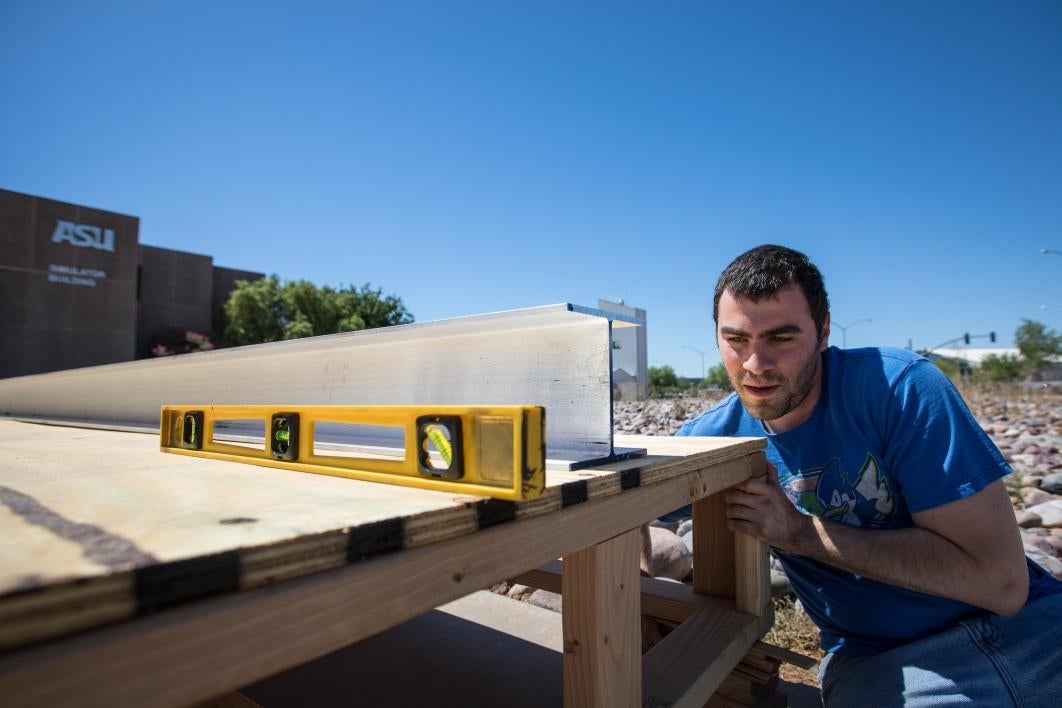 A man places shims to level out a metal track