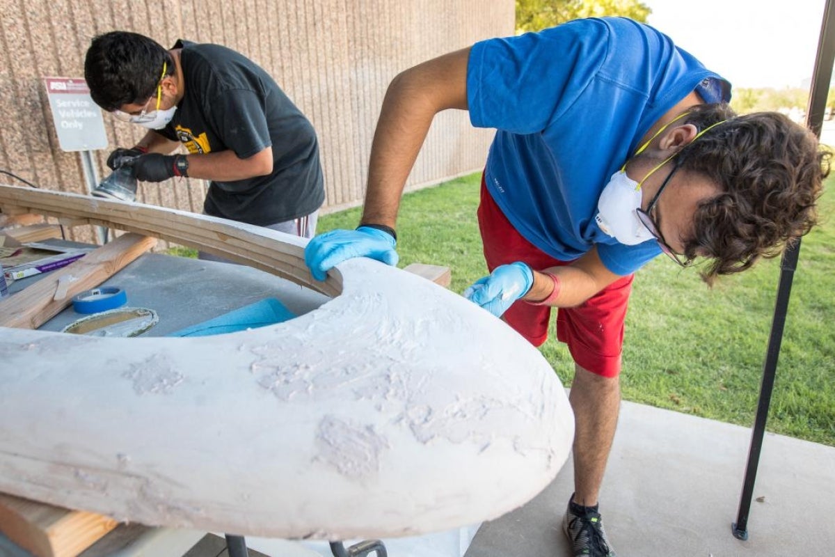 AZLoop team members sand the wooden pod model