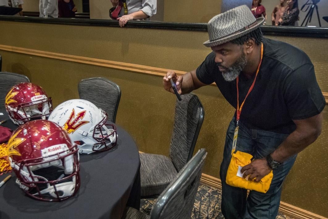 man taking photo of football helmets