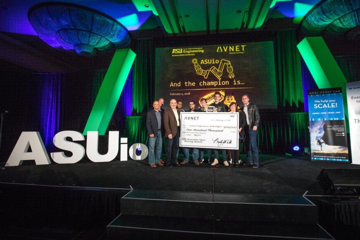 team on stage holding giant check