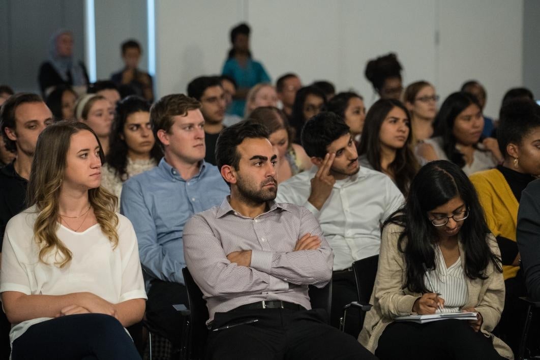 crowd of students sitting, listening, taking notes in an auditorium