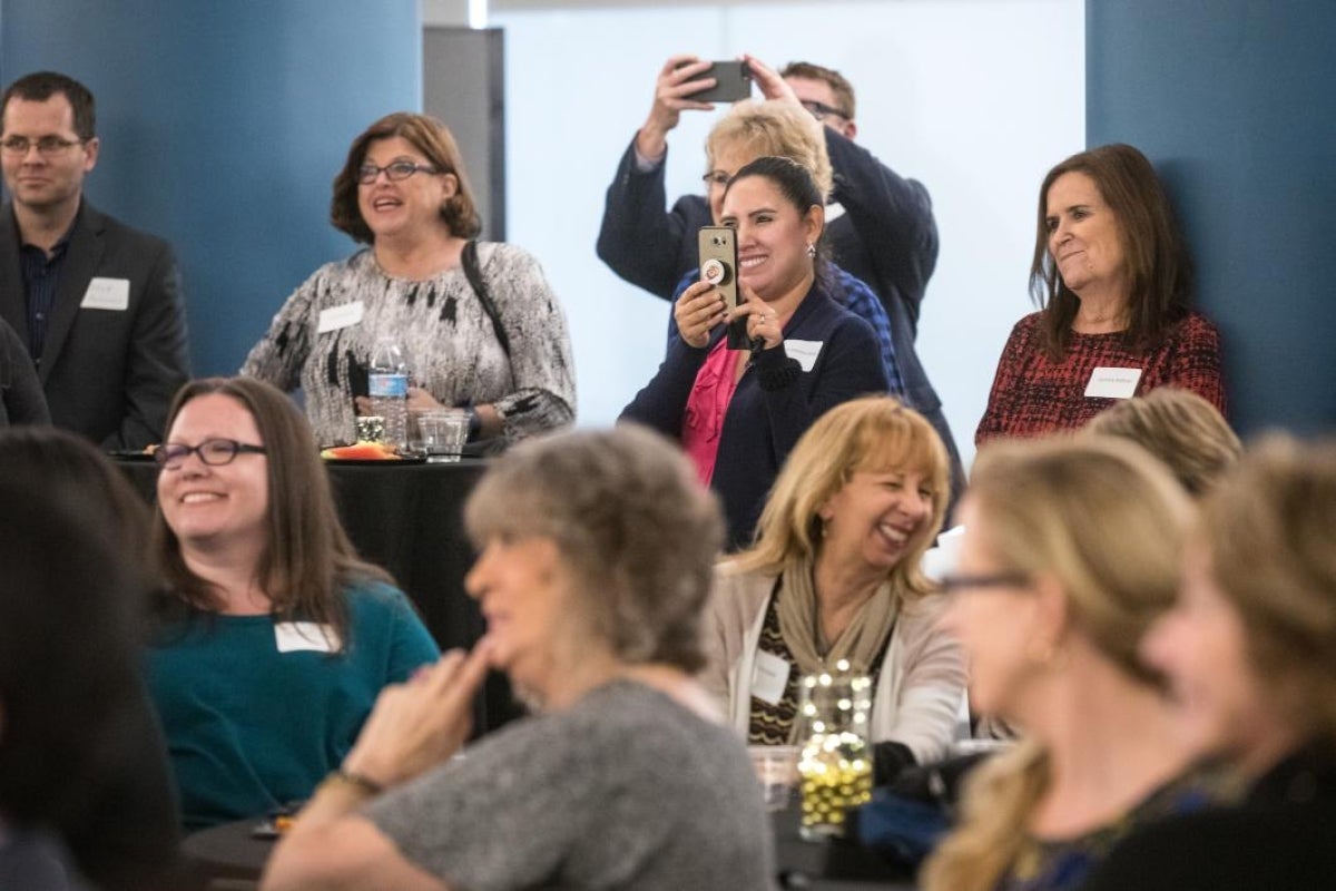 group of people listening to someone talk and take pictures