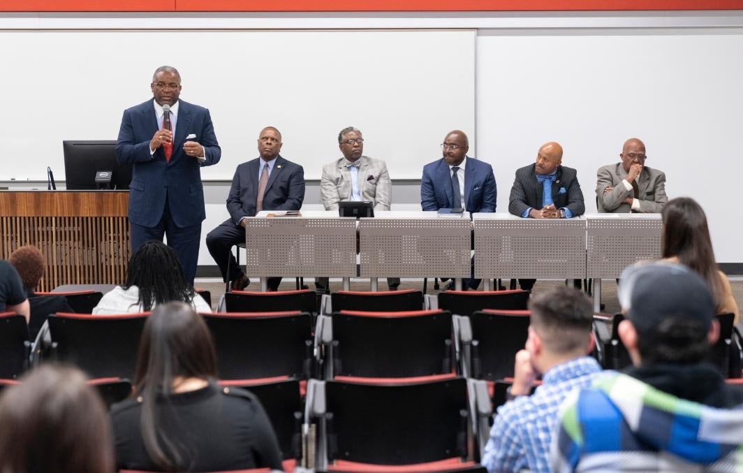 A man speaks in front of a panel