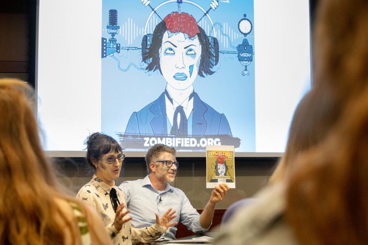 two people talking in front of projector screen