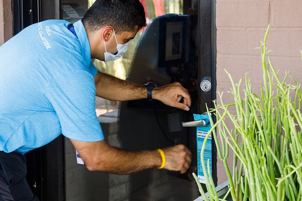 A man leaves an informational door hanger at a residence.