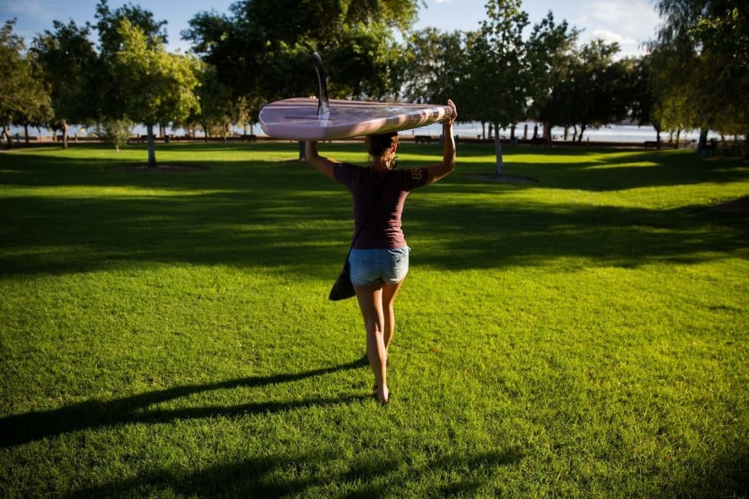 Woman carrying a paddle board.