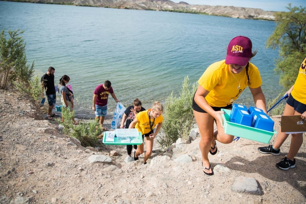 Students carry chemical tests from a beach.