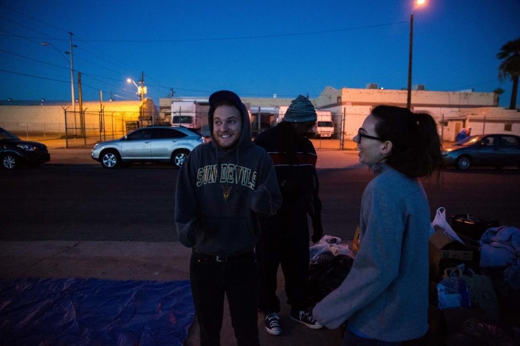 man and woman standing outside next to donation boxes