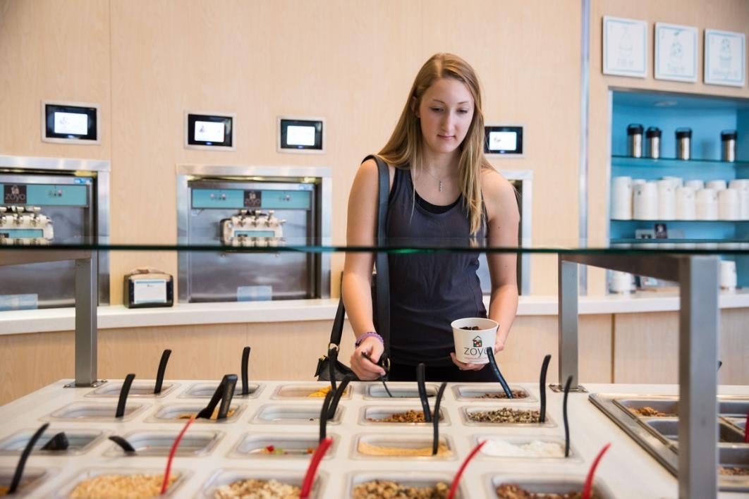 Woman putting toppings on her yogurt.