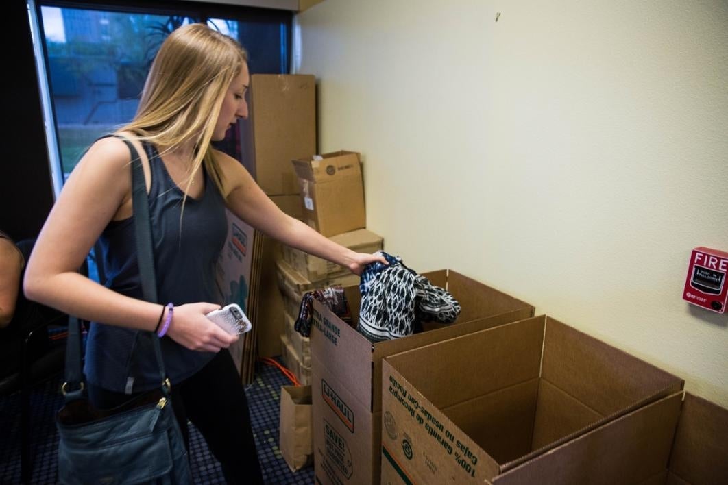 Woman tosses a dress into a box.