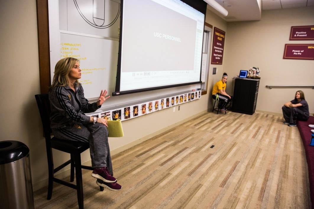 Woman sitting next to a projection screen.