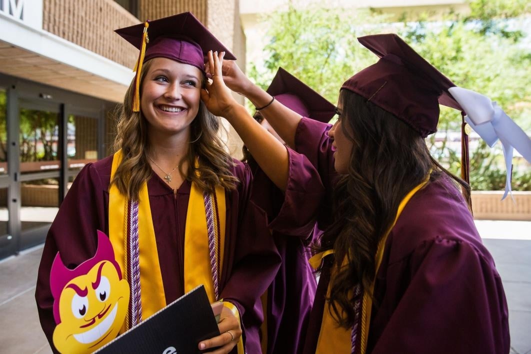 friends helping grad adjust mortar board