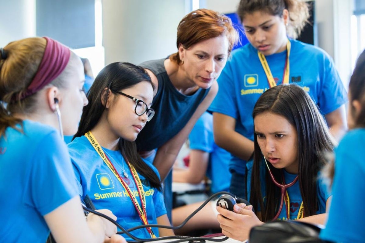 professor oversees students working with stethoscopes