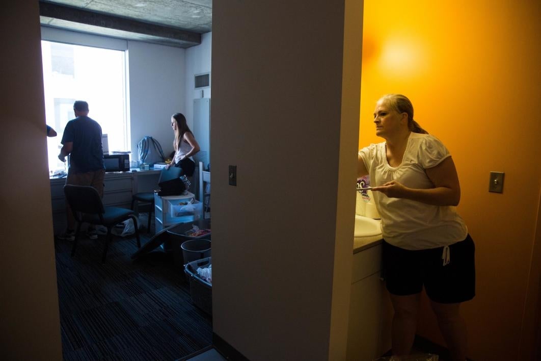 woman adjusting shelves in dorm bathroom