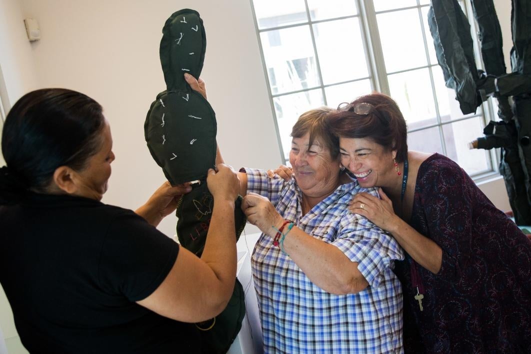 Women construct cloth cactuses with immigration stories embroidered on them.