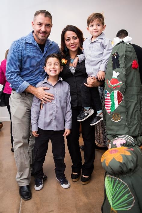 A family poses with a cloth cactus embroidered with their immigration story.