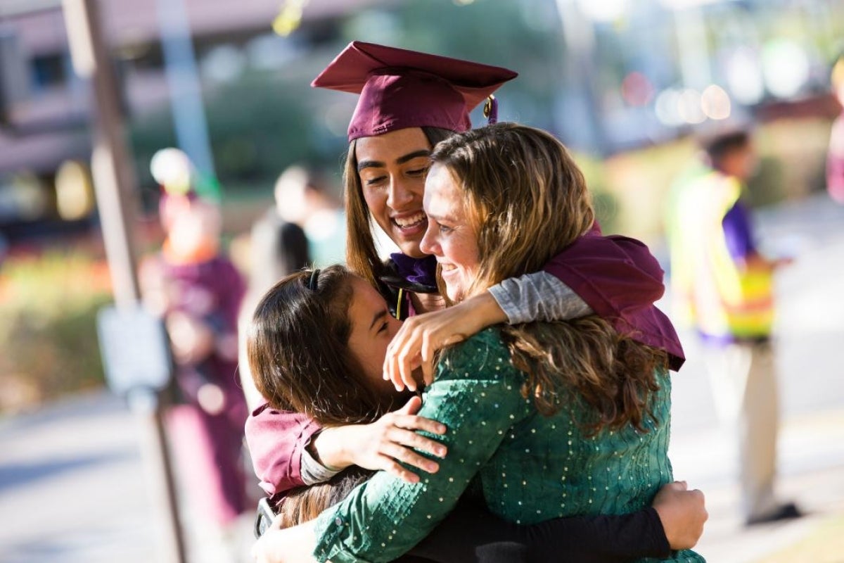 ASU graduate hugging friends