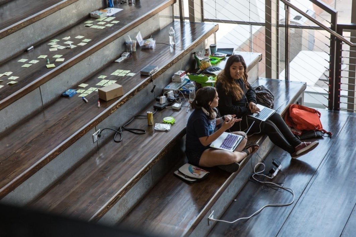 Students discuss their project sitting on the stairs during the hackathon