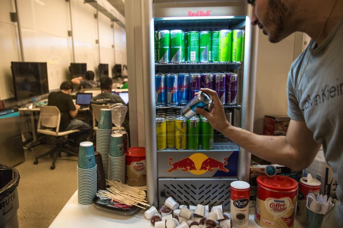 A student pulls a Red Bull out of a mini fridge at the hackathon