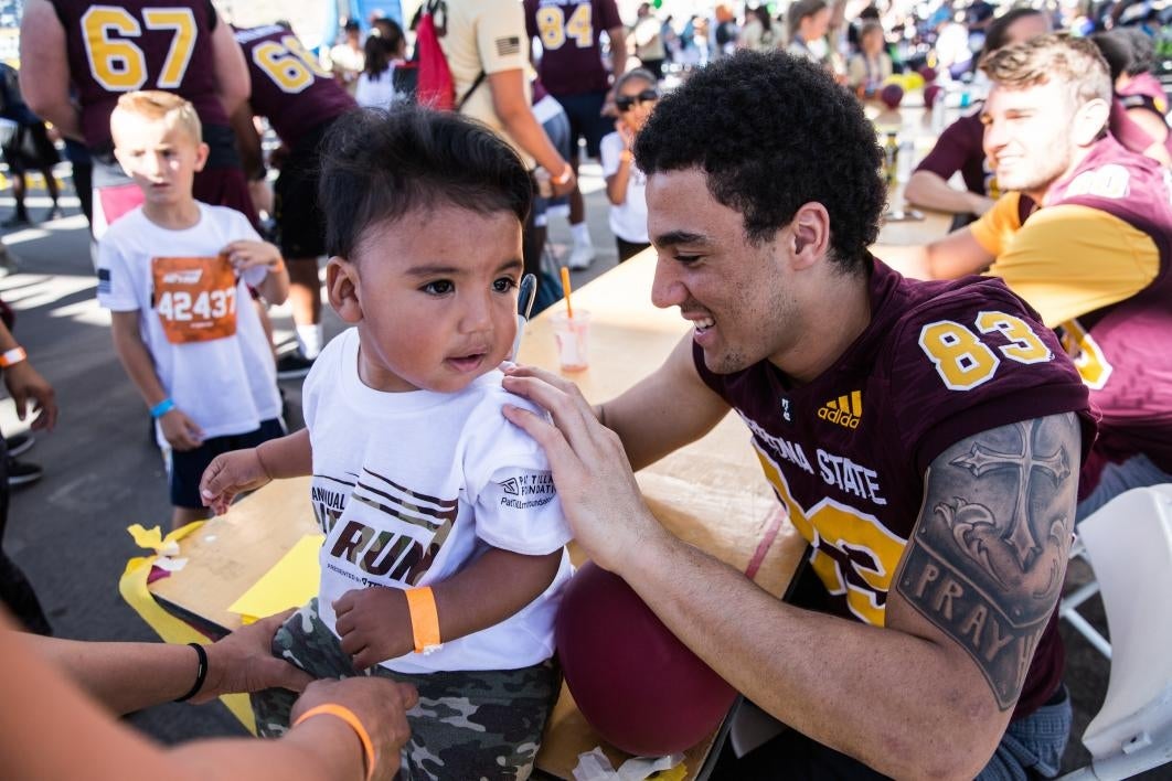 An ASU football player signs the shirt of a tiny tot after the 2017 Pats Run