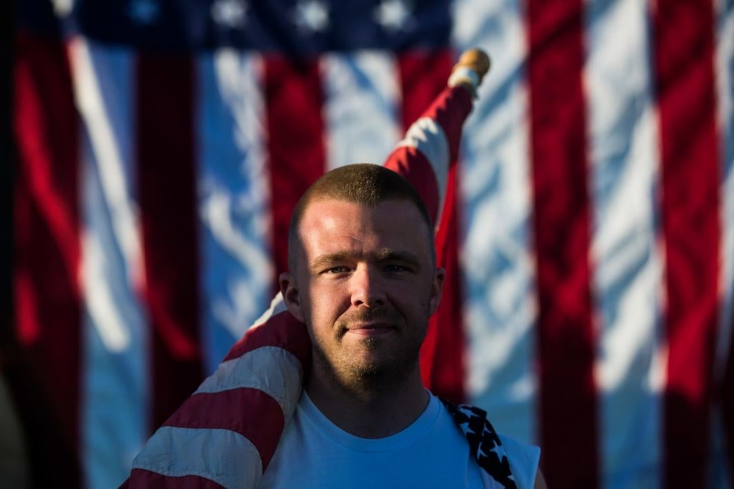 A man stands with a US flag before Pats Run 2017