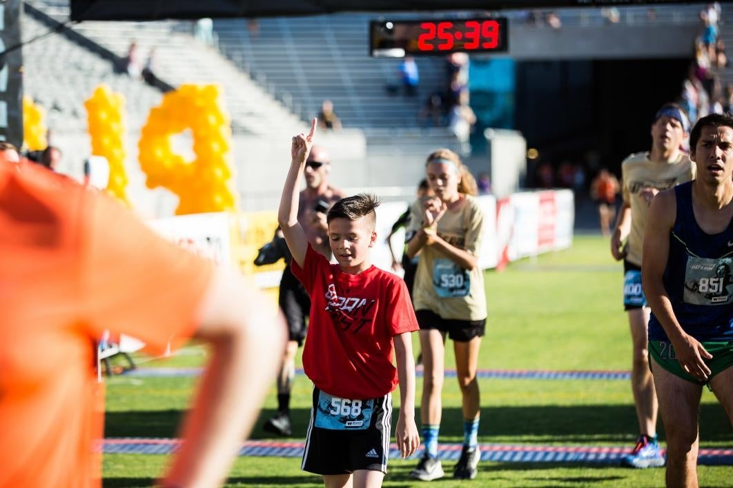 A boy is the first kid to cross the finish line at Pats Run