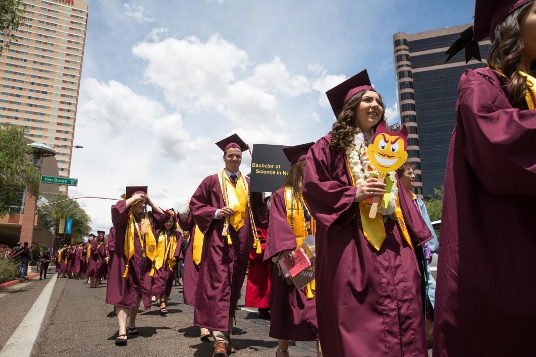 graduates walking down downtown street