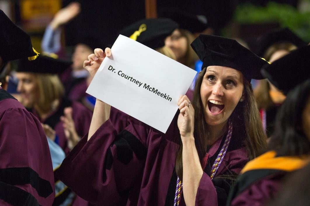 student holding up paper with name on it