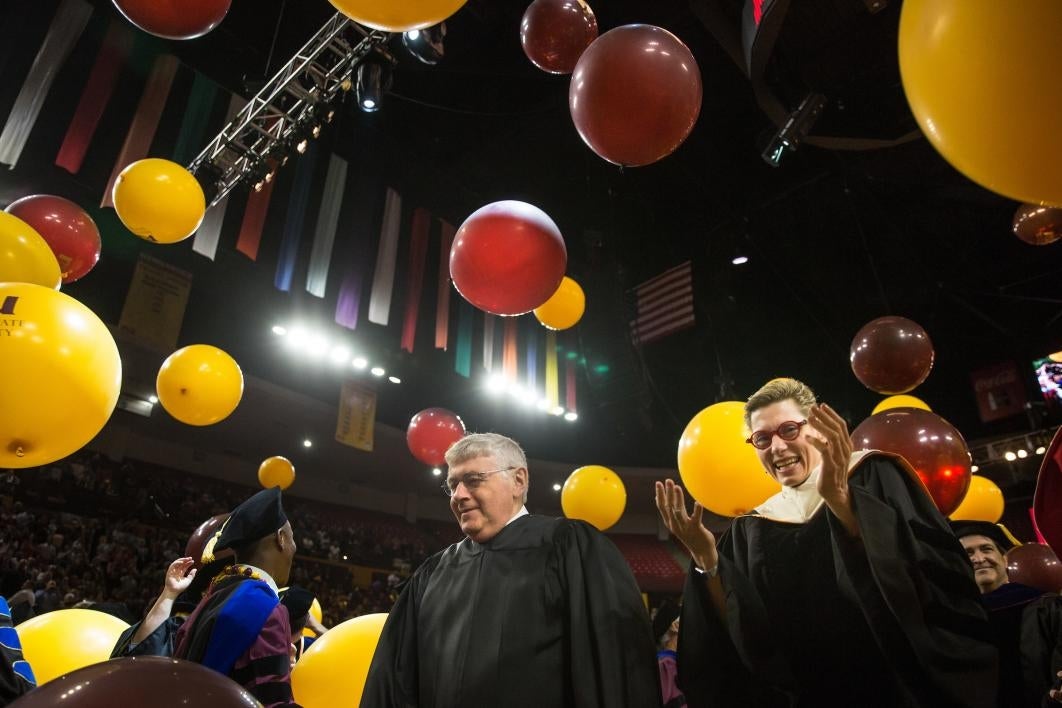 people walking under graduation balloons