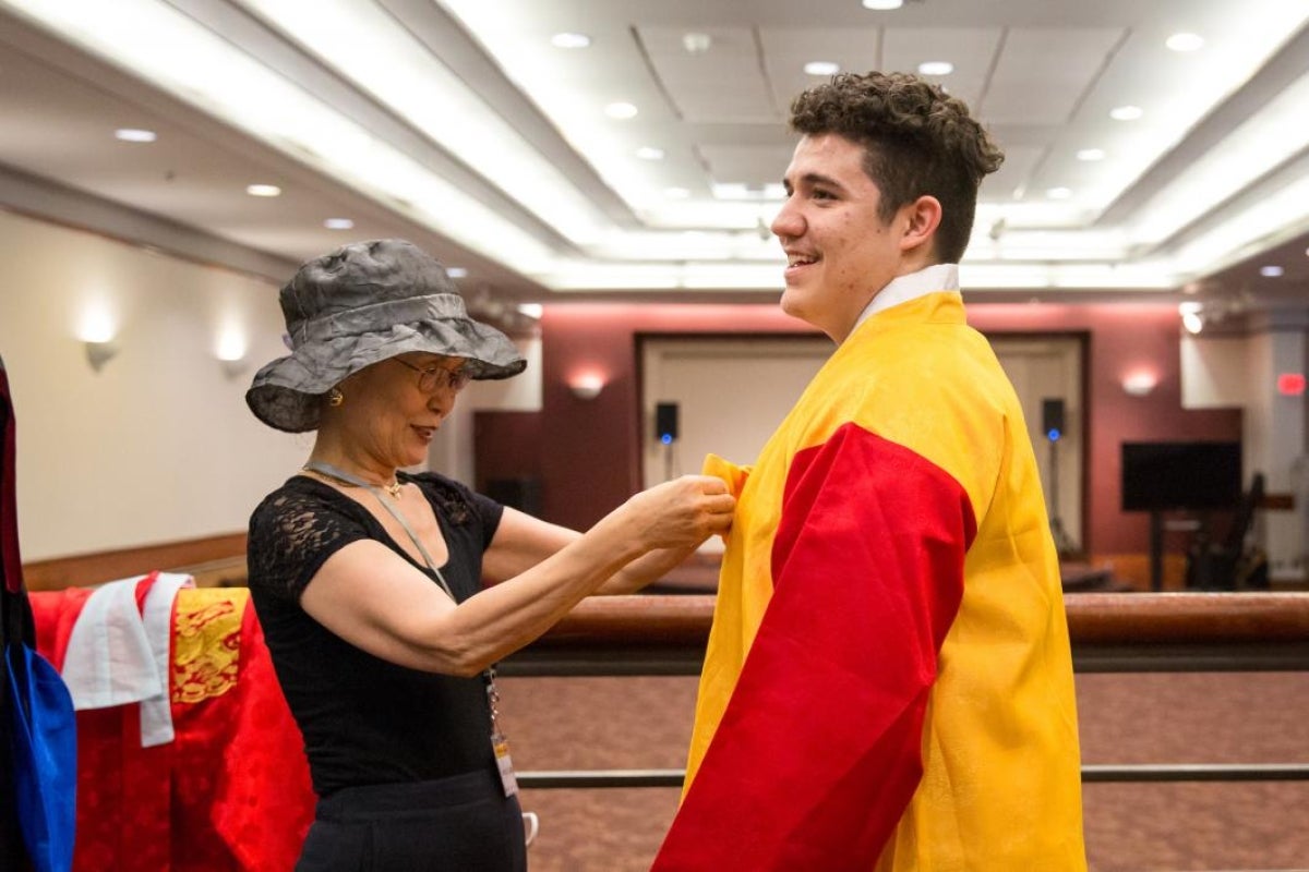 A retired faculty member helps a student don traditional Korean robes for a demonstration