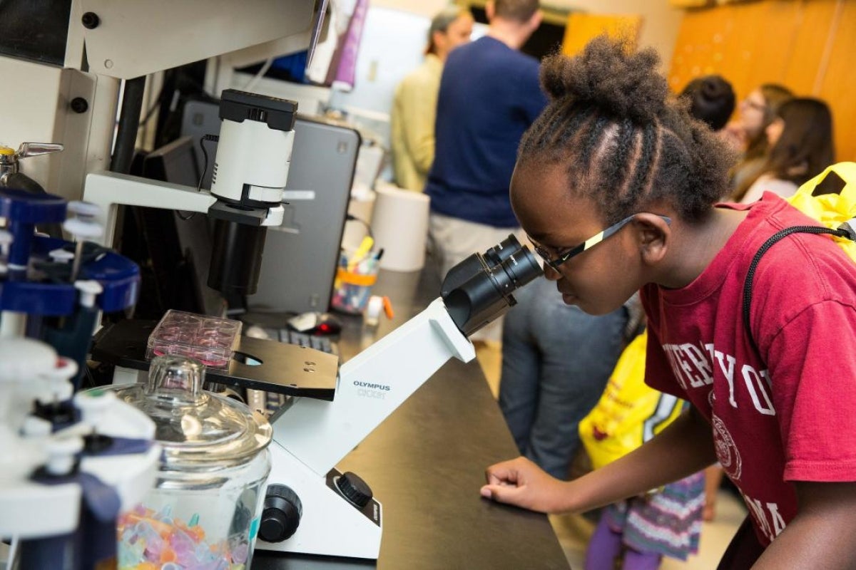 child looking into microscope