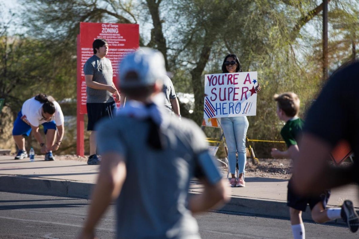 woman holding a sign that says You're A Superhero