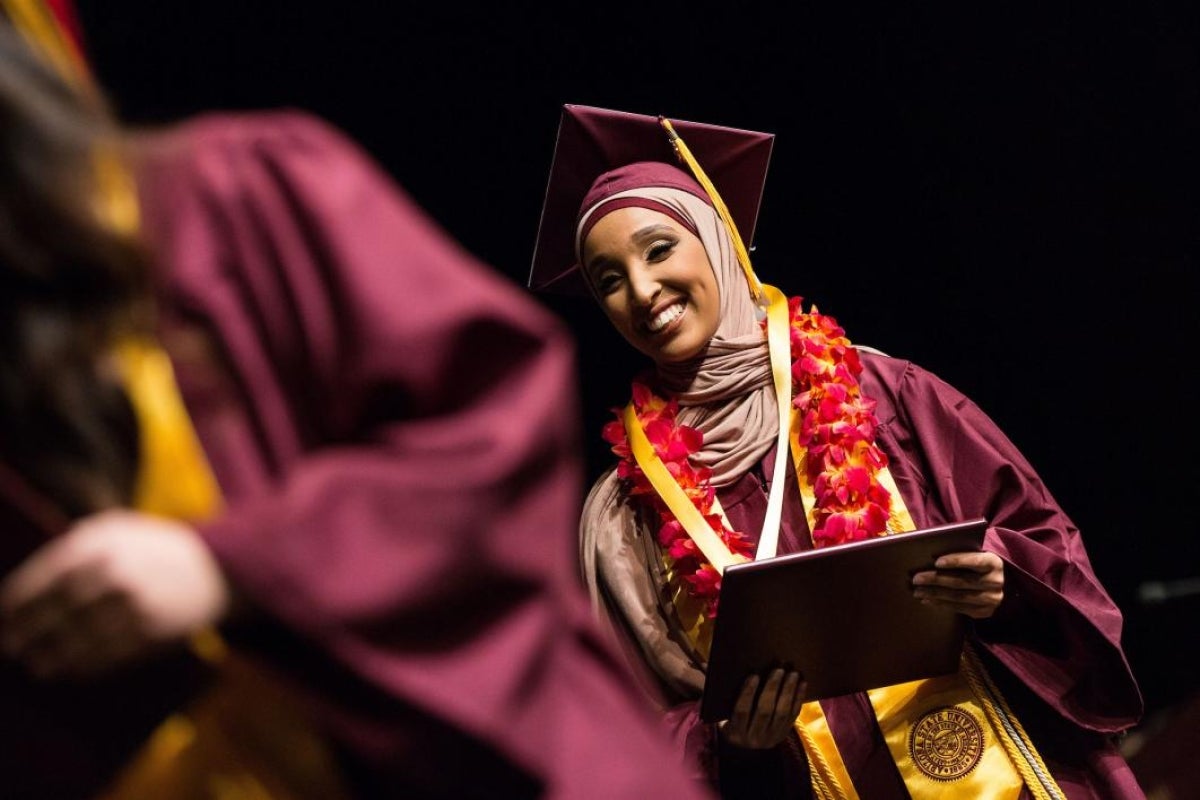 student walking across graduation stage