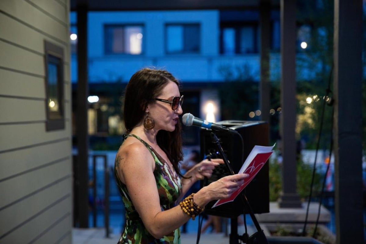 woman speaking into microphone on a stage, reading