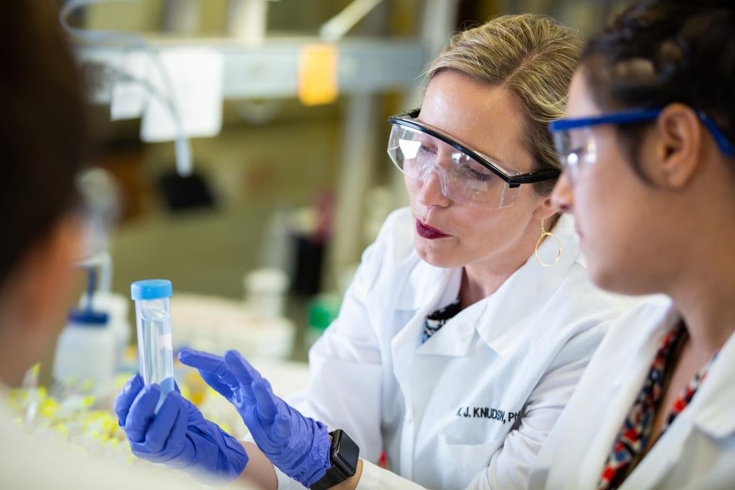 photo of Knudson showing water sample to students