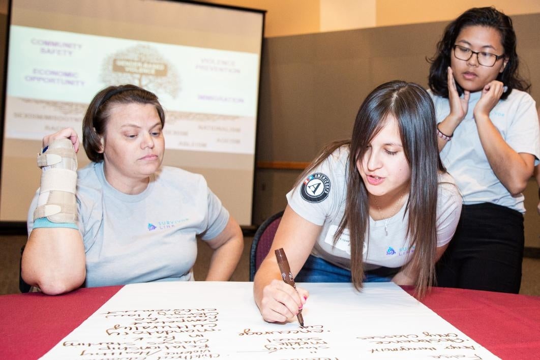 Participants at a conference on preventing domestic violence write ideas on a poster