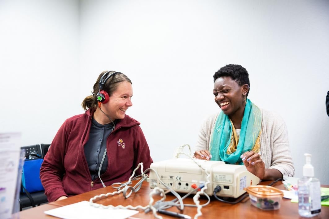 two women laugh during a hearing test