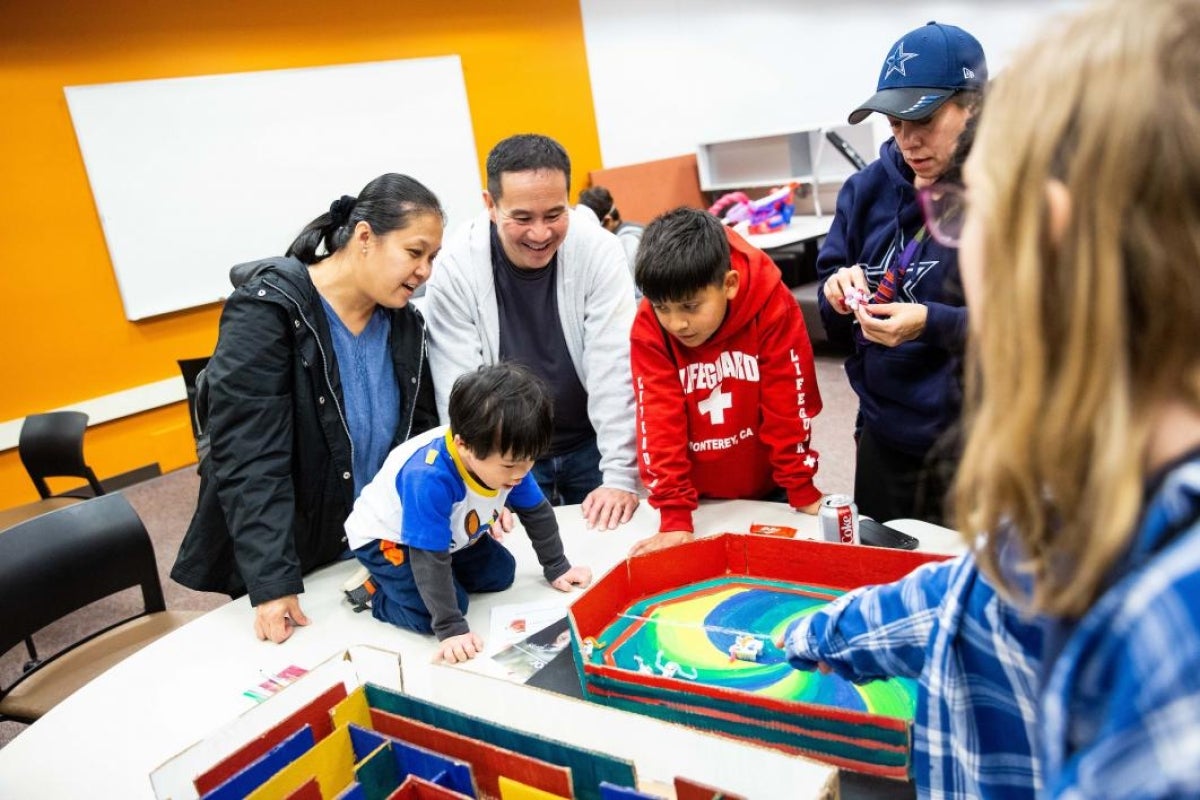 little boy and family watch mini robots battle