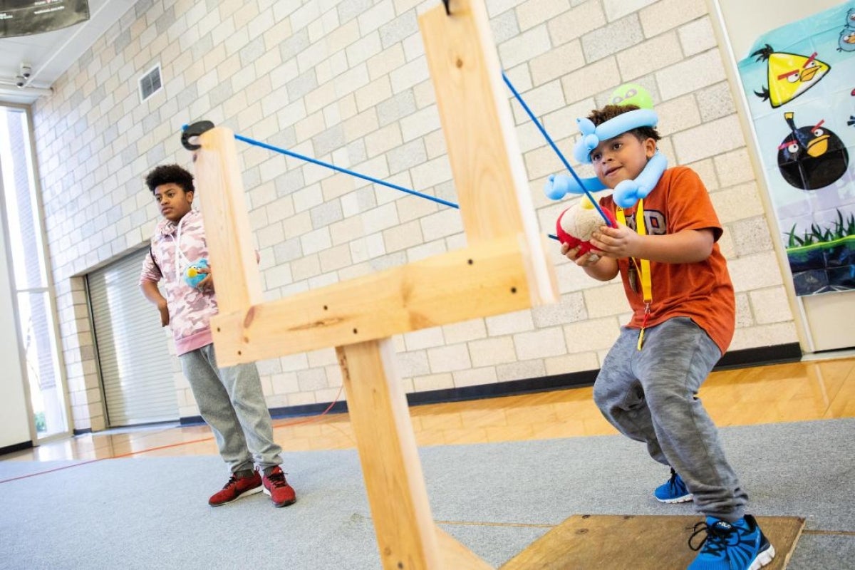 boy uses a giant slingshot to launch a toy