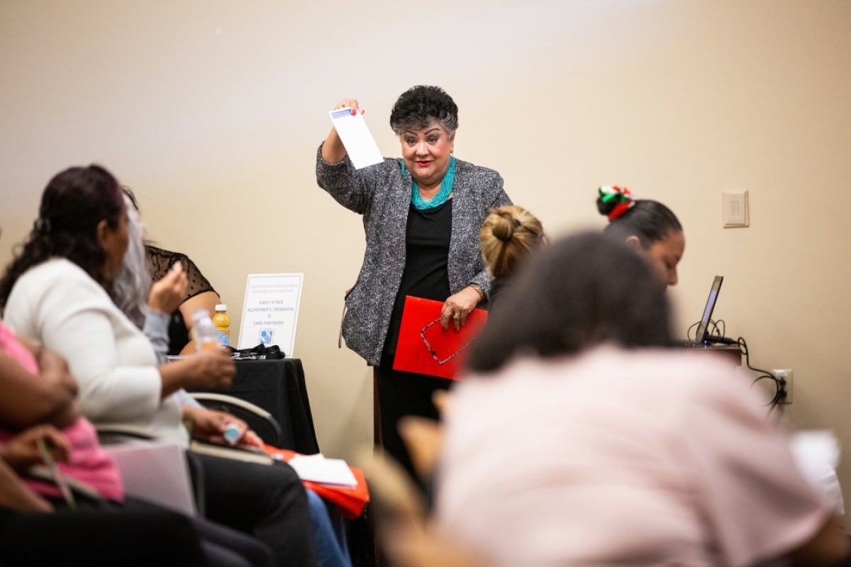 woman holding up a paper to a crowd of people