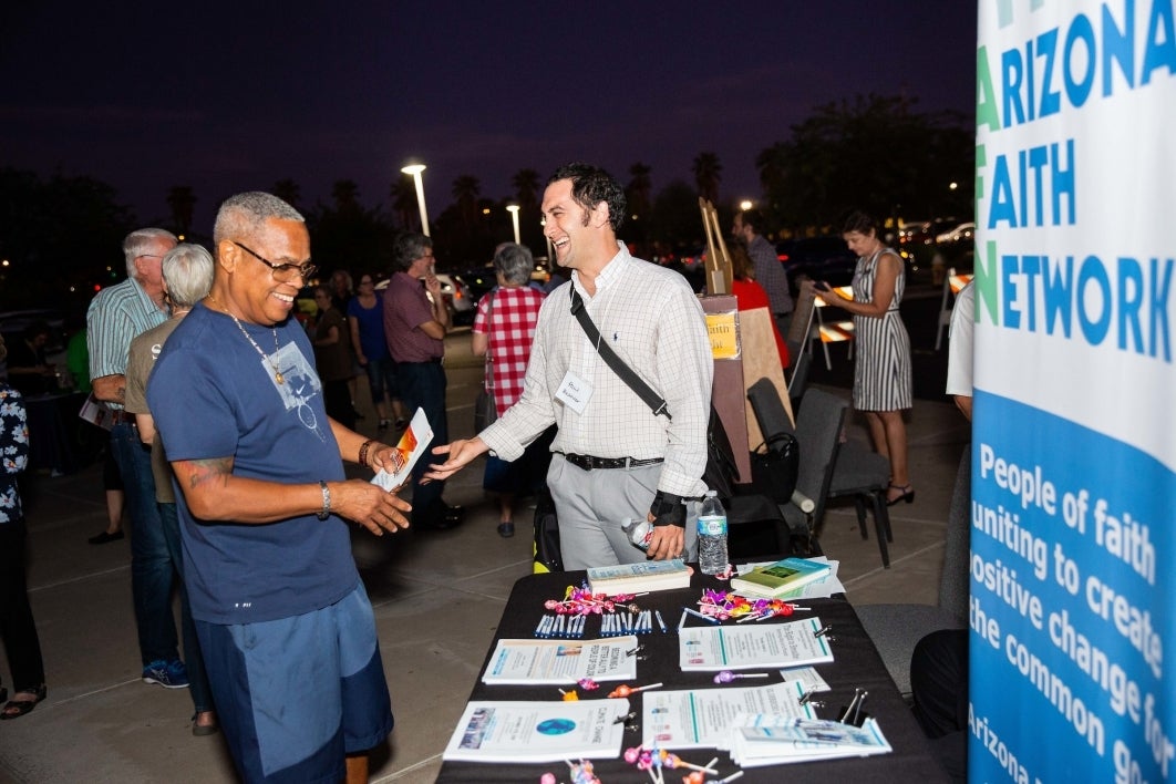 Men speak at a table about the Arizona Faith Network